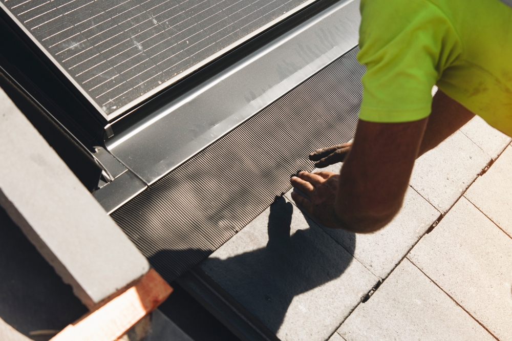 Worker installing roofing materials on a bright sunny day in an urban setting