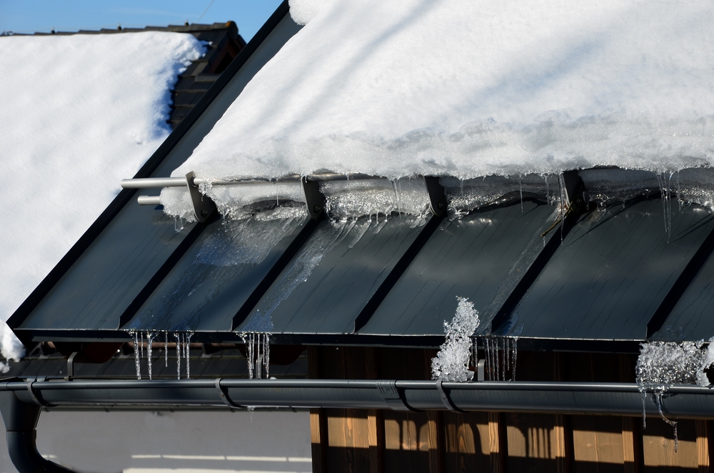 Galvanized metal roof in the mountains featuring a snow guard bar to prevent rapid snow and ice sliding
